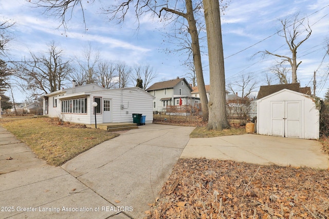 bungalow-style house featuring an outdoor structure, fence, a shed, and a chimney