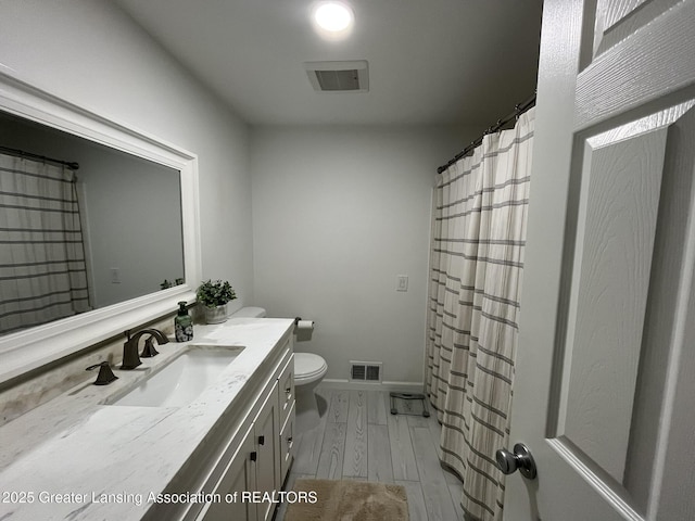 bathroom featuring vanity, wood finished floors, visible vents, baseboards, and toilet