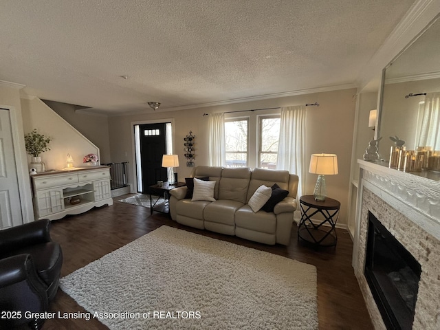 living area featuring a glass covered fireplace, a textured ceiling, dark wood finished floors, and ornamental molding