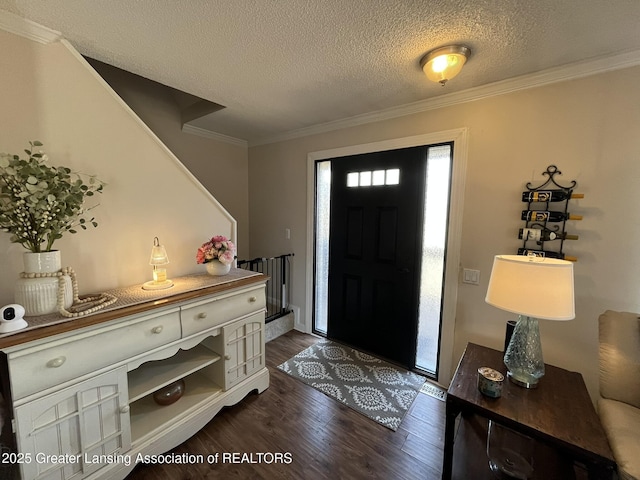 entrance foyer with dark wood-type flooring, ornamental molding, and a textured ceiling