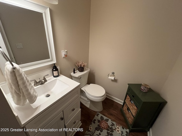 bathroom with baseboards, toilet, wood finished floors, and vanity