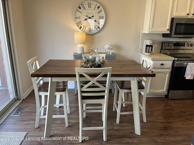 dining space featuring visible vents, baseboards, and dark wood finished floors