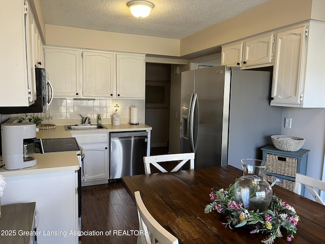 kitchen featuring dark wood-style floors, a sink, light countertops, appliances with stainless steel finishes, and backsplash