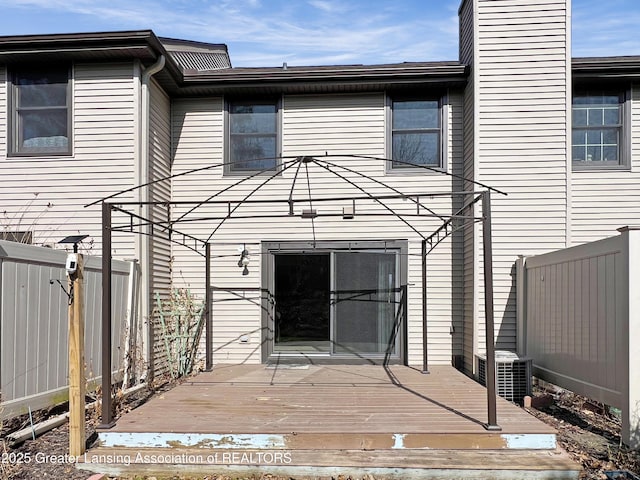 rear view of house featuring a wooden deck, central AC, a fenced backyard, and a chimney