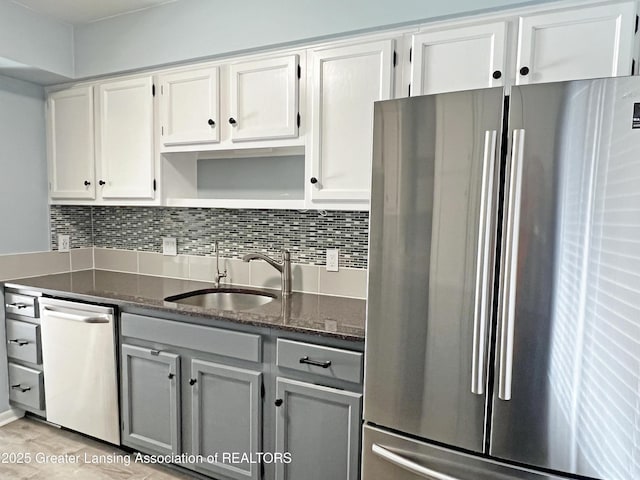 kitchen with tasteful backsplash, dark stone countertops, appliances with stainless steel finishes, and a sink