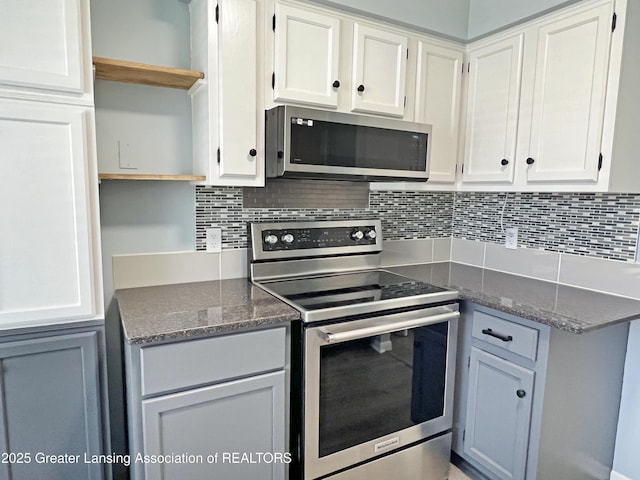 kitchen featuring decorative backsplash, dark stone countertops, white cabinets, stainless steel appliances, and open shelves