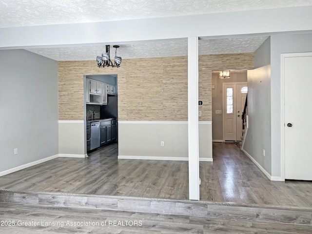 interior space with a notable chandelier, wood finished floors, and a textured ceiling