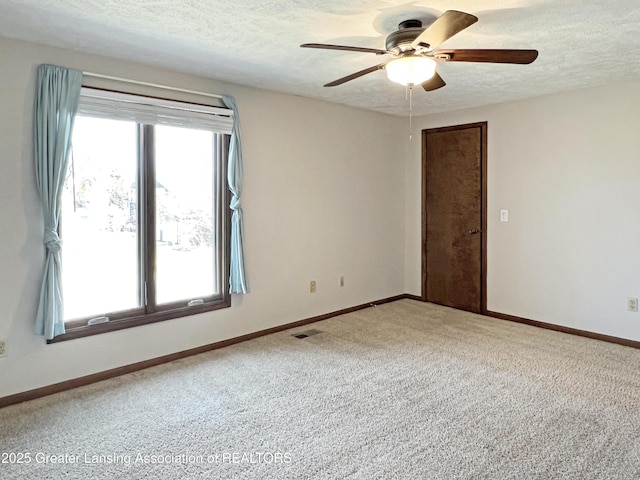 spare room featuring visible vents, baseboards, ceiling fan, carpet floors, and a textured ceiling