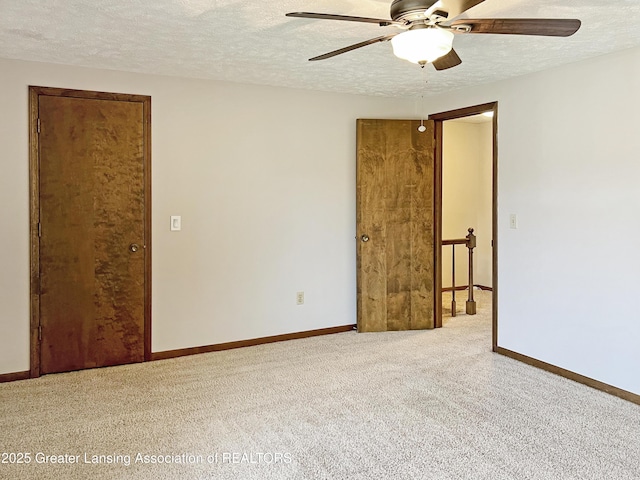 carpeted empty room with baseboards, a textured ceiling, and ceiling fan