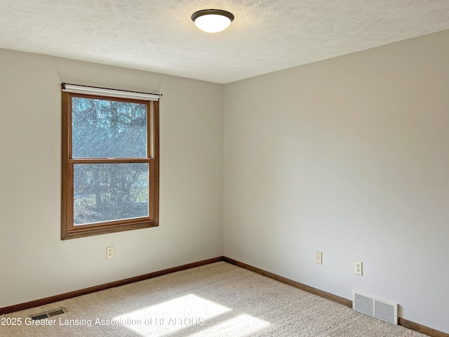 carpeted empty room with baseboards, visible vents, and a textured ceiling