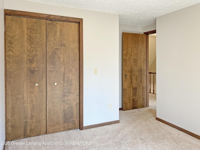 unfurnished bedroom with baseboards, carpet floors, a textured ceiling, and a closet