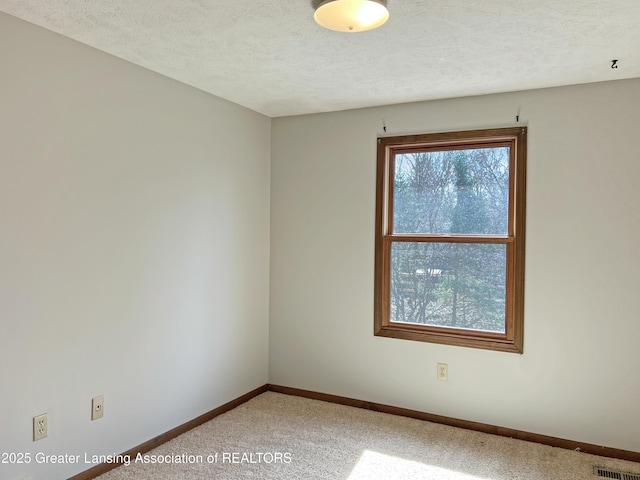 unfurnished room with visible vents, baseboards, a textured ceiling, and light carpet