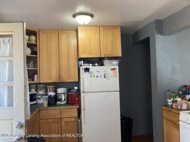 kitchen with light brown cabinetry, white appliances, and tile counters