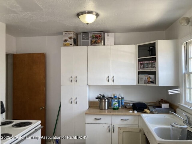 kitchen with a sink, white cabinets, electric stove, and light countertops