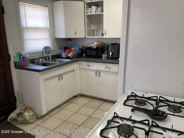 kitchen featuring a sink, open shelves, dark countertops, black microwave, and white gas range