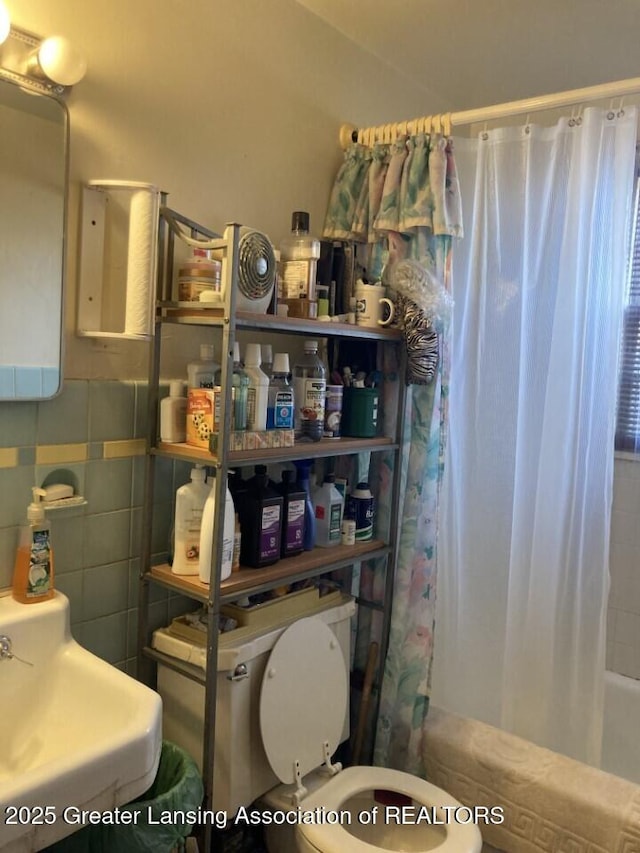 full bathroom featuring a sink, toilet, tile walls, and shower / tub combo