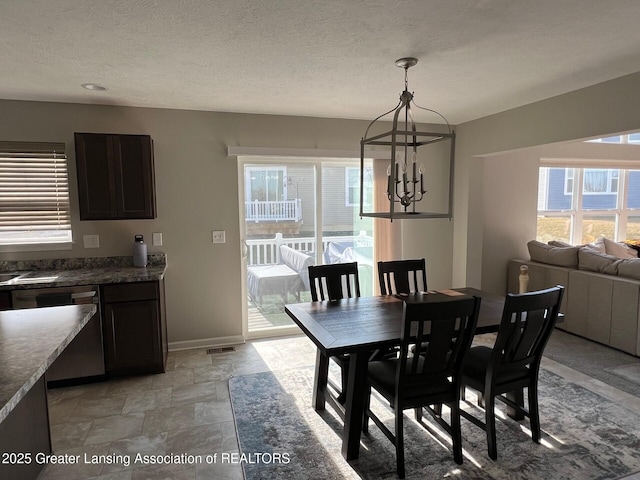 dining area featuring visible vents, baseboards, a chandelier, stone finish floor, and a textured ceiling