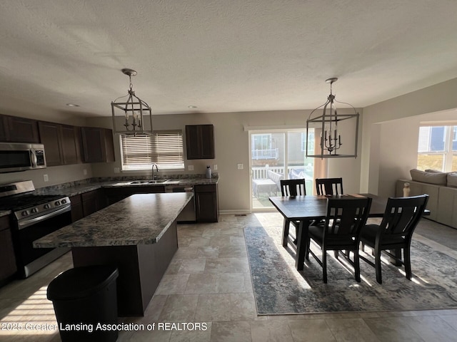 kitchen with a sink, plenty of natural light, appliances with stainless steel finishes, and a chandelier