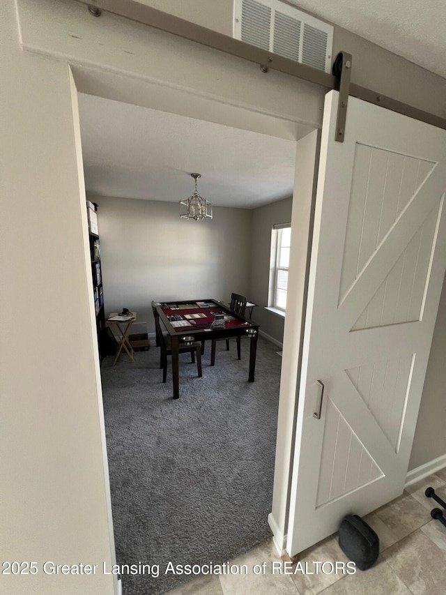 dining space featuring visible vents, baseboards, carpet, a chandelier, and a barn door