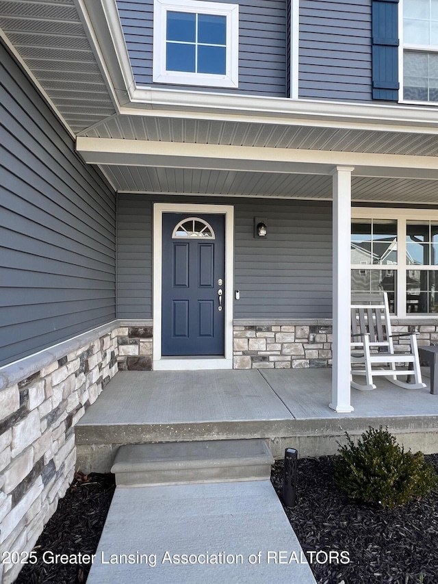 doorway to property with stone siding and a porch