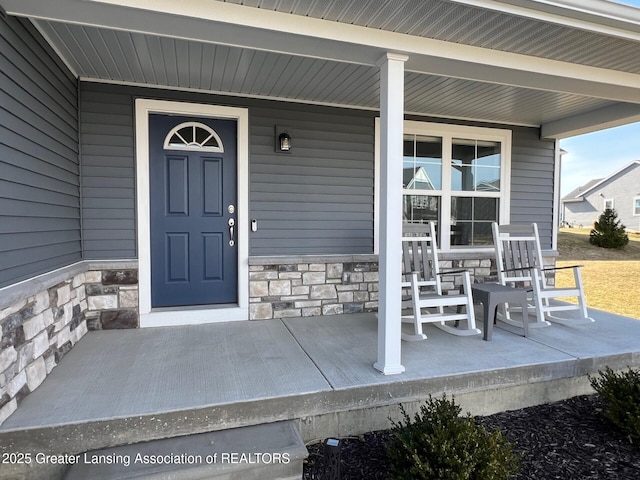 doorway to property featuring stone siding and a porch