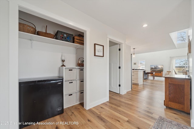 kitchen with a skylight, recessed lighting, light wood-style floors, and baseboards