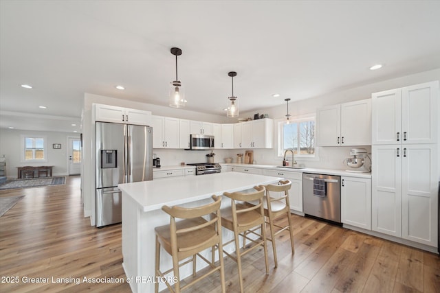 kitchen featuring light wood-type flooring, a sink, stainless steel appliances, white cabinets, and light countertops