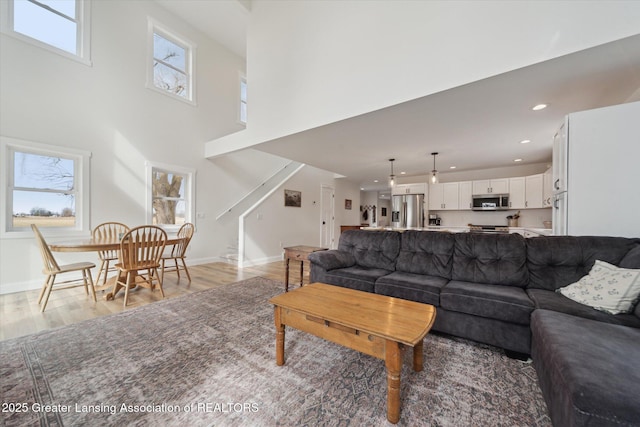 living room with recessed lighting, stairway, baseboards, and light wood finished floors