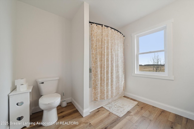 full bathroom with baseboards, toilet, wood finished floors, and shower / bath combo