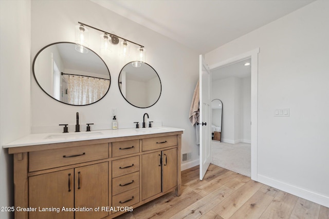 full bathroom with a sink, visible vents, wood finished floors, and double vanity