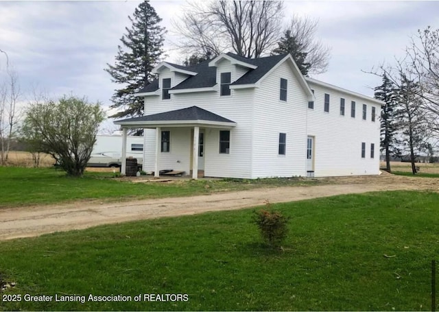 view of front of property featuring dirt driveway, a front lawn, and a shingled roof