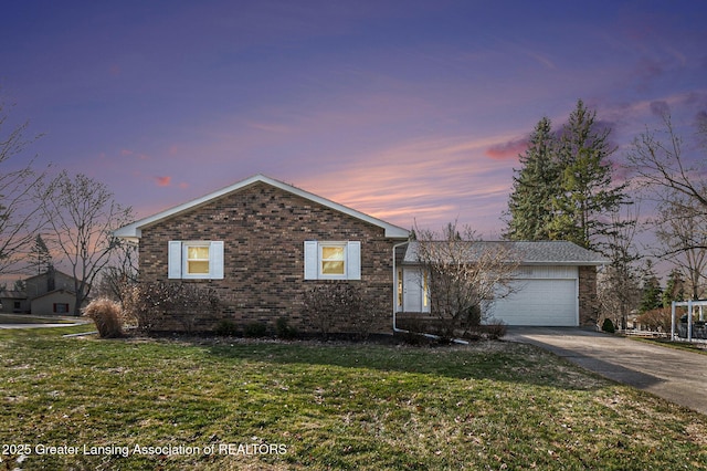 view of front of house with concrete driveway, a garage, a lawn, and brick siding