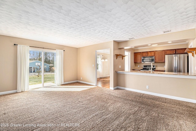 unfurnished living room with a textured ceiling, baseboards, and light carpet