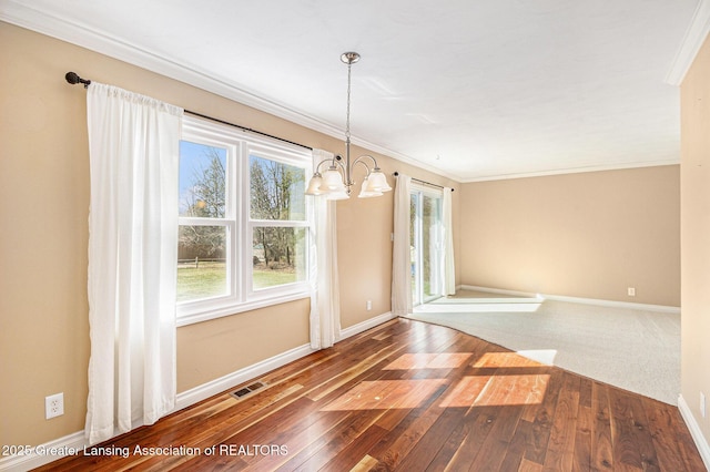 unfurnished dining area with baseboards, visible vents, ornamental molding, hardwood / wood-style flooring, and a chandelier