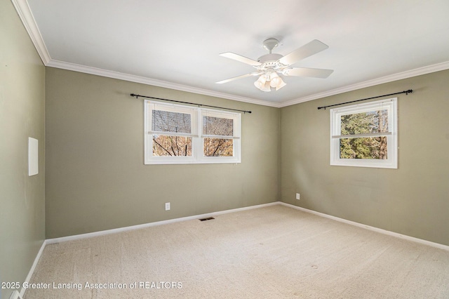 carpeted spare room with a ceiling fan, crown molding, baseboards, and visible vents