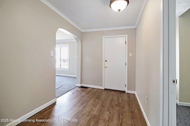 entrance foyer featuring baseboards, wood finished floors, arched walkways, and ornamental molding