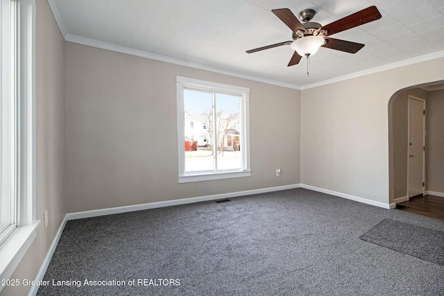 empty room featuring arched walkways, a ceiling fan, crown molding, and baseboards