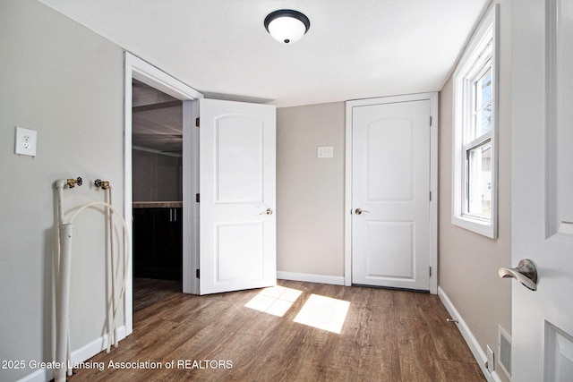 unfurnished bedroom with visible vents, baseboards, a closet, and wood finished floors