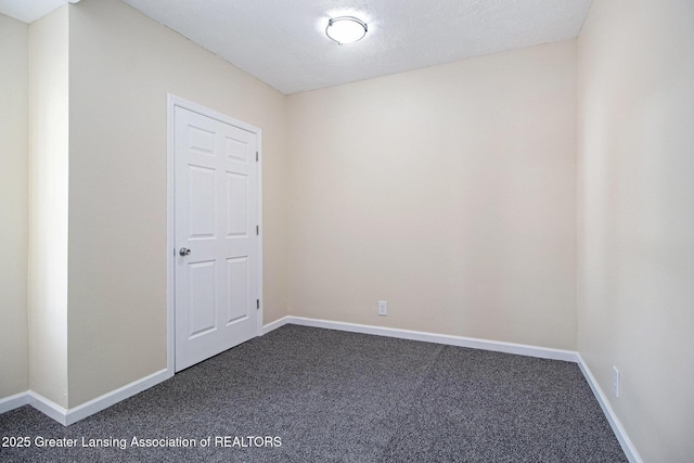 unfurnished room featuring dark colored carpet and baseboards