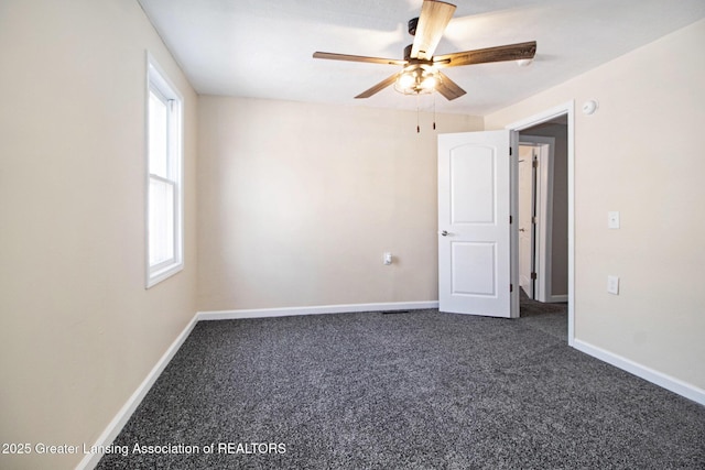 empty room with baseboards, ceiling fan, and dark colored carpet