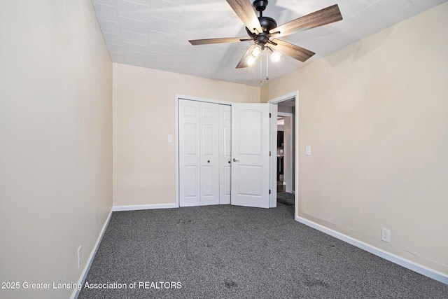 unfurnished bedroom with a closet, baseboards, ceiling fan, and dark carpet