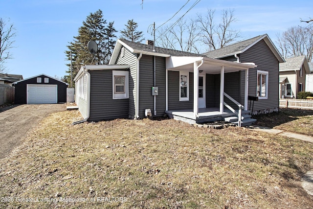 bungalow-style house featuring fence, covered porch, a garage, an outbuilding, and driveway