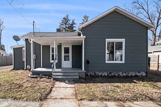 view of front of home featuring a porch, a chimney, and fence