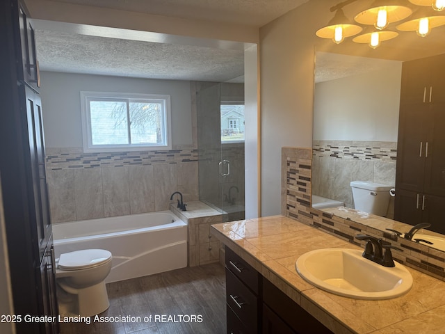 full bath with toilet, a textured ceiling, wood finished floors, a bath, and vanity