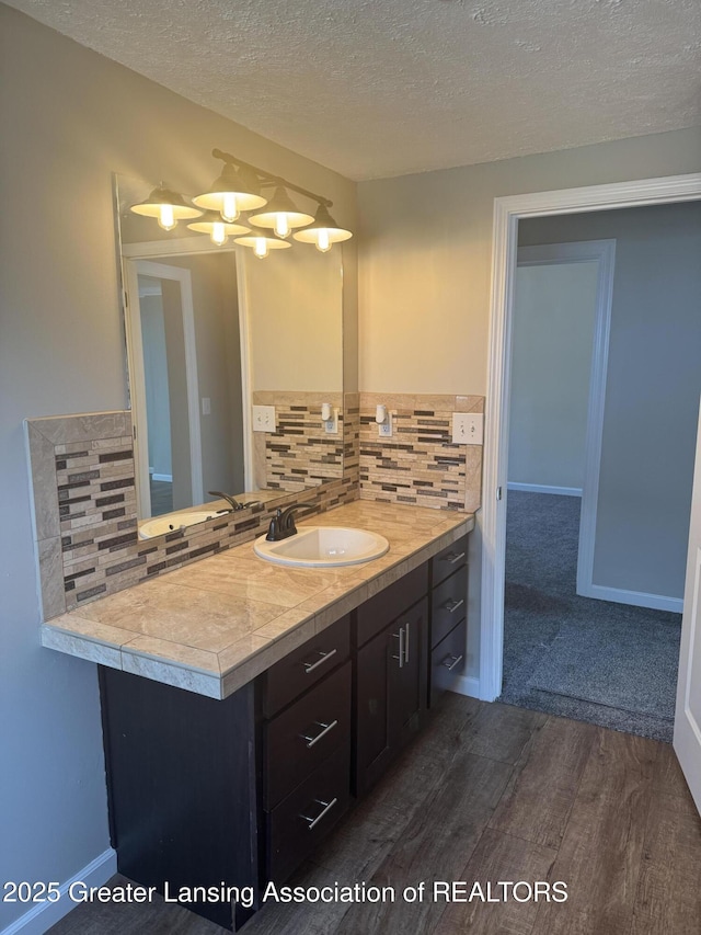 bathroom with vanity, decorative backsplash, wood finished floors, and baseboards