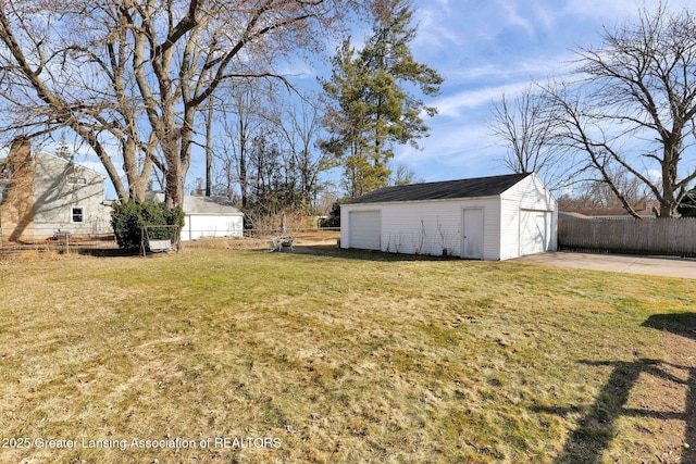 view of yard featuring an outbuilding, fence, and a garage