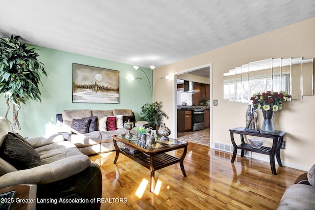 living area featuring visible vents, baseboards, and wood finished floors