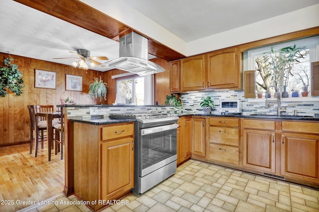 kitchen featuring electric range, a ceiling fan, a sink, a peninsula, and island range hood