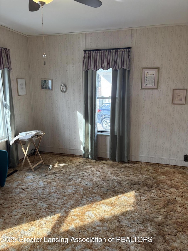 empty room featuring wallpapered walls, carpet, and ceiling fan