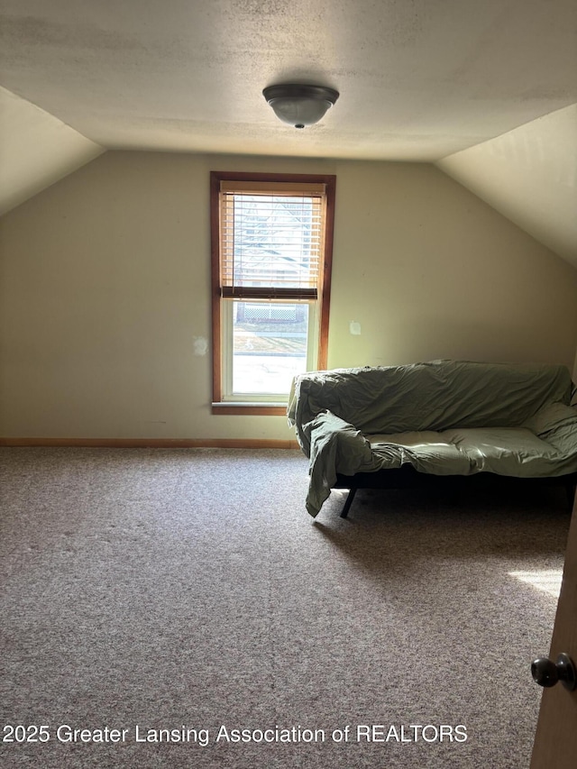 unfurnished bedroom featuring vaulted ceiling, carpet flooring, baseboards, and a textured ceiling